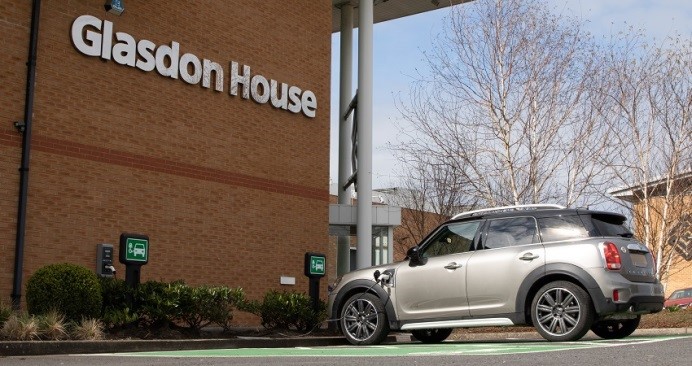 Un coche eléctrico gris se carga frente a Glasdon House